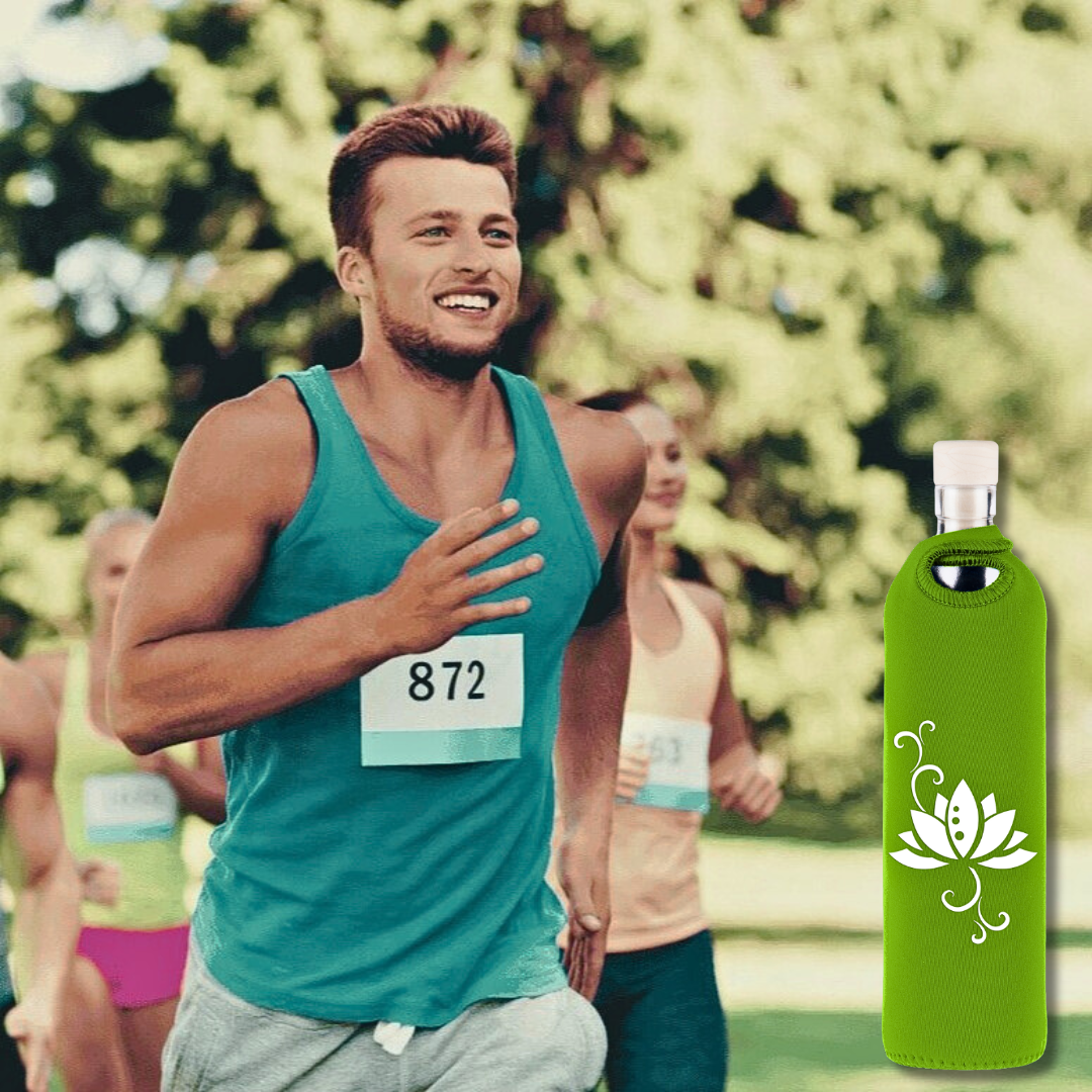 Man running an outdoor race, smiling, with a green glass water bottle in a neoprene sleeve featuring a white lotus design placed on the right side of the image.